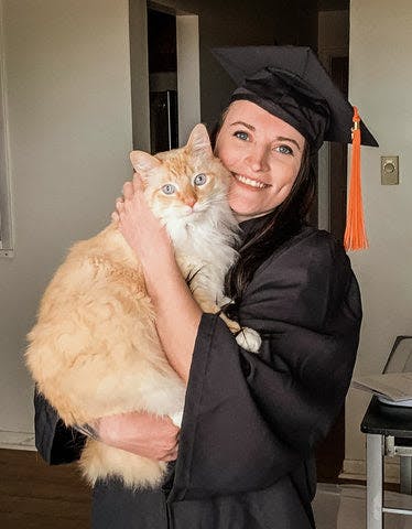 a woman in a graduation gown holding a cat